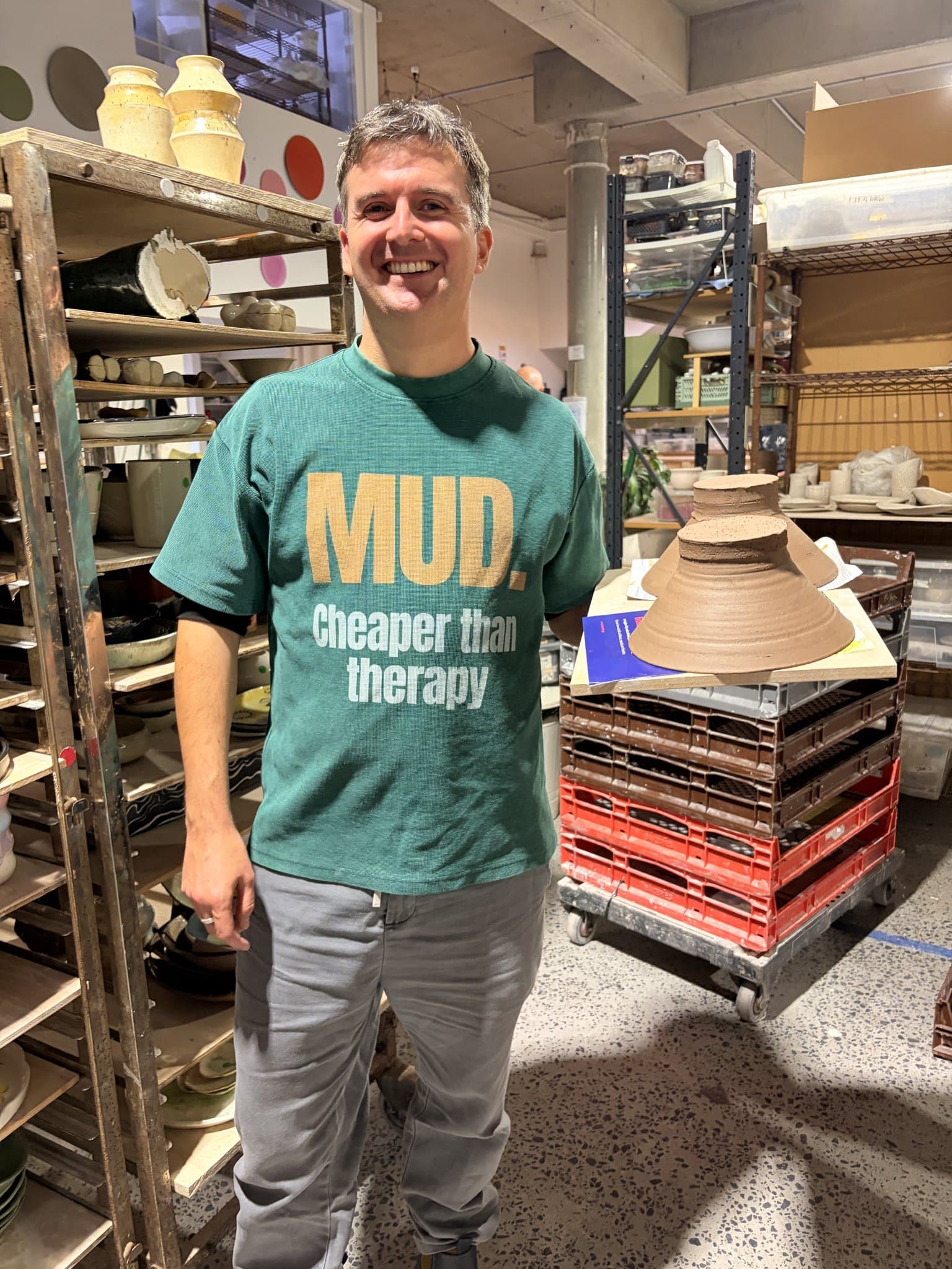A studio owner among racks of work in a busy pottery studio.