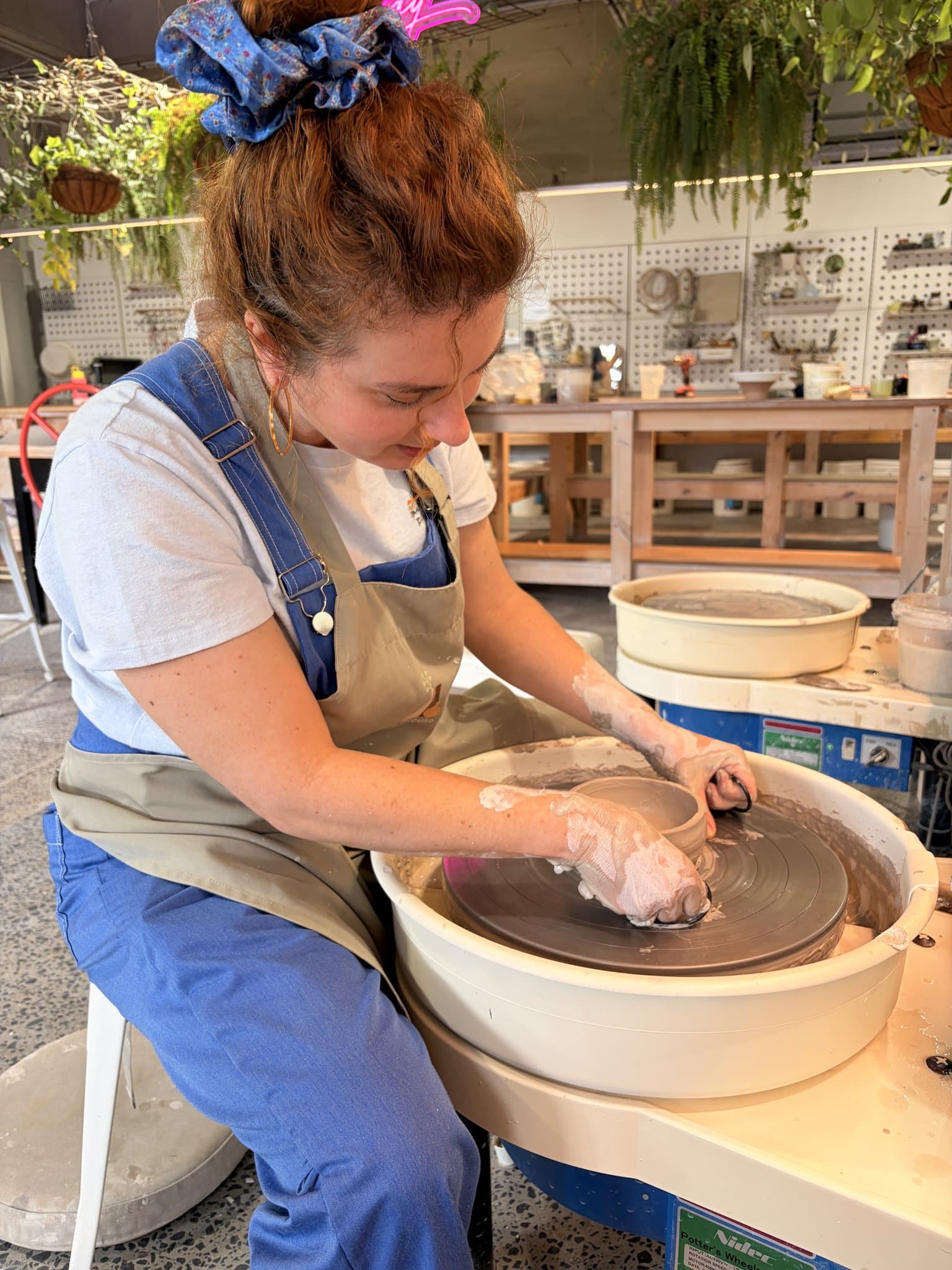 A member throwing a pot on the wheel at a pottery studio.