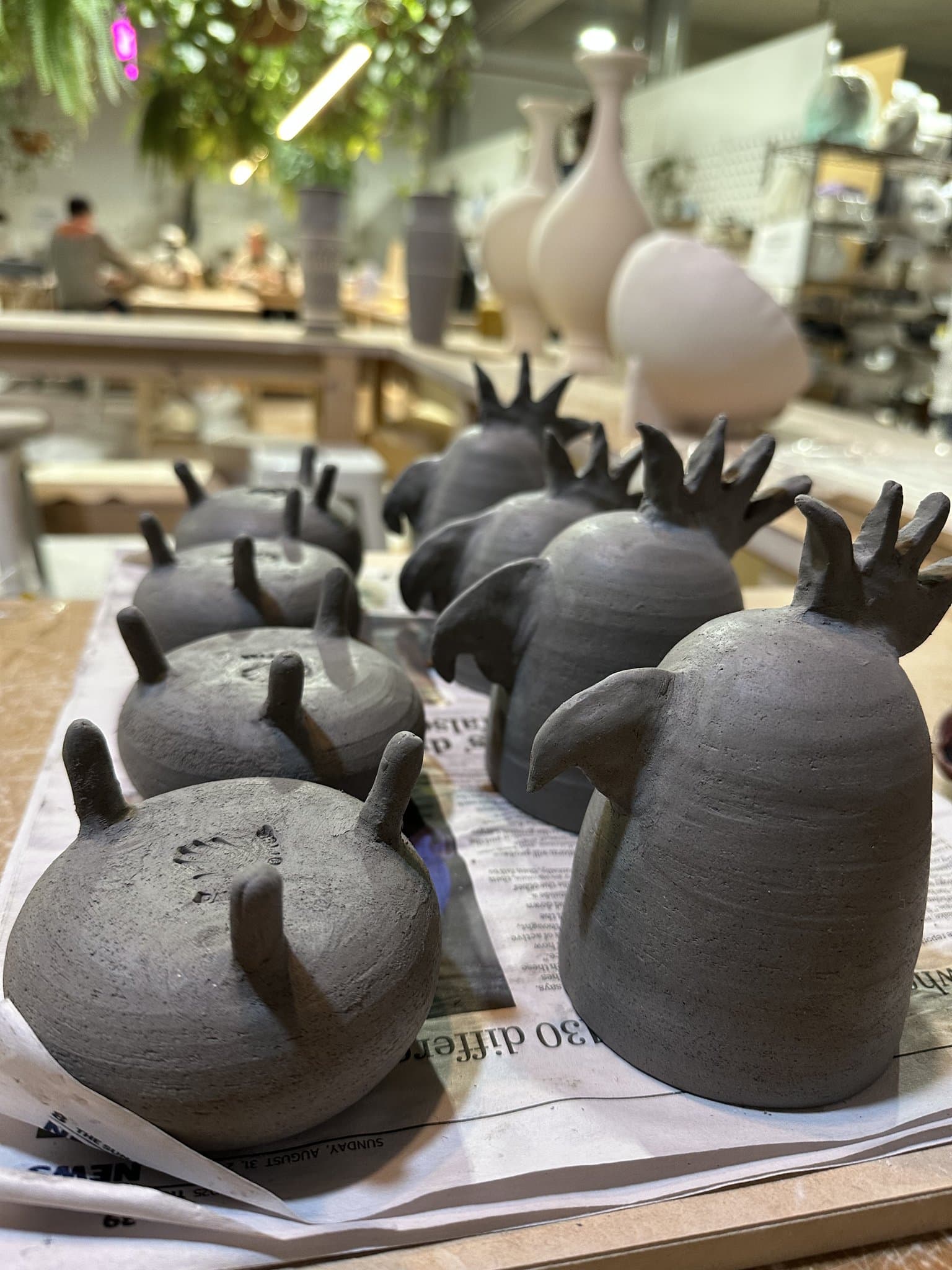A tray of class pieces drying at a busy pottery studio.